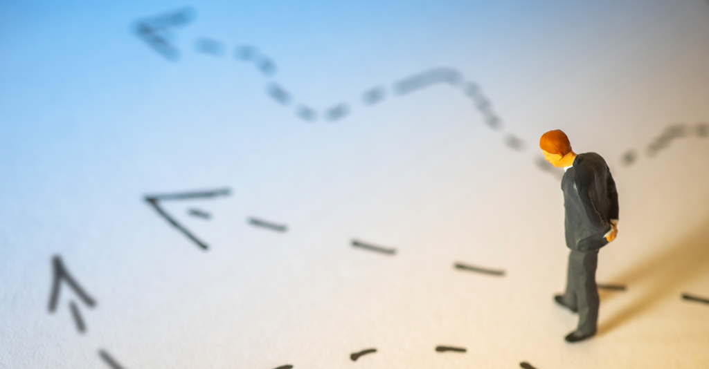 A toy model business man standing over arrows written on a piece of paper.