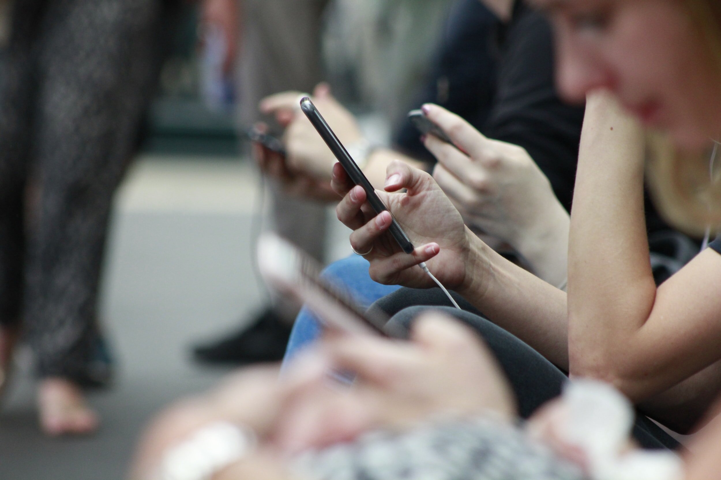 People sitting in a row as they use their mobile devices.