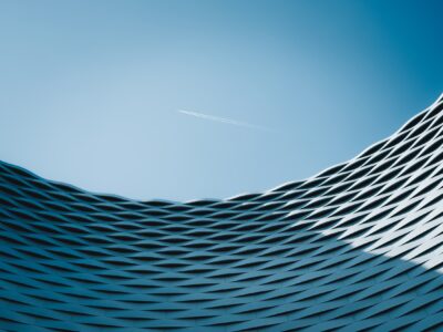 Abstract image of a textural building with an airplane flying in the distance.