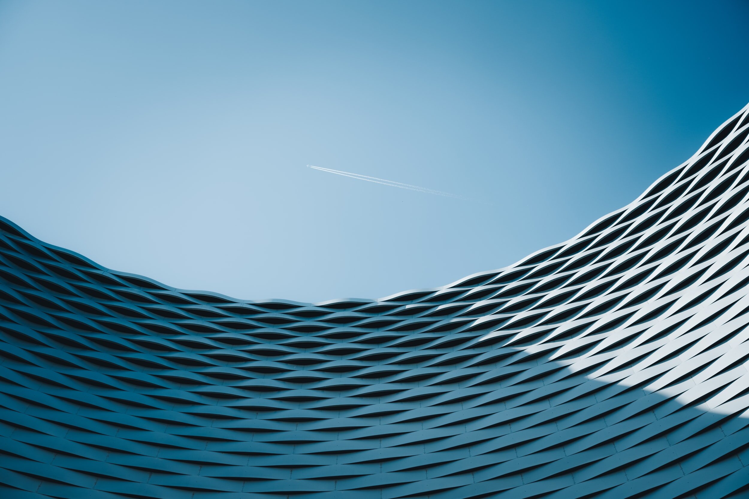 Abstract image of a textural building with an airplane flying in the distance.