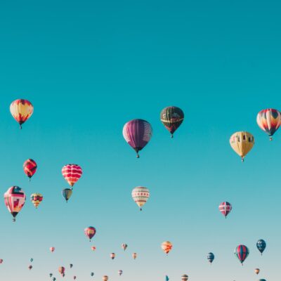 Numerous hot air balloons against a bright blue sky.