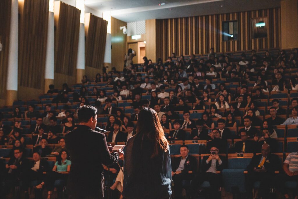 A man and woman speaking in front of an audience.