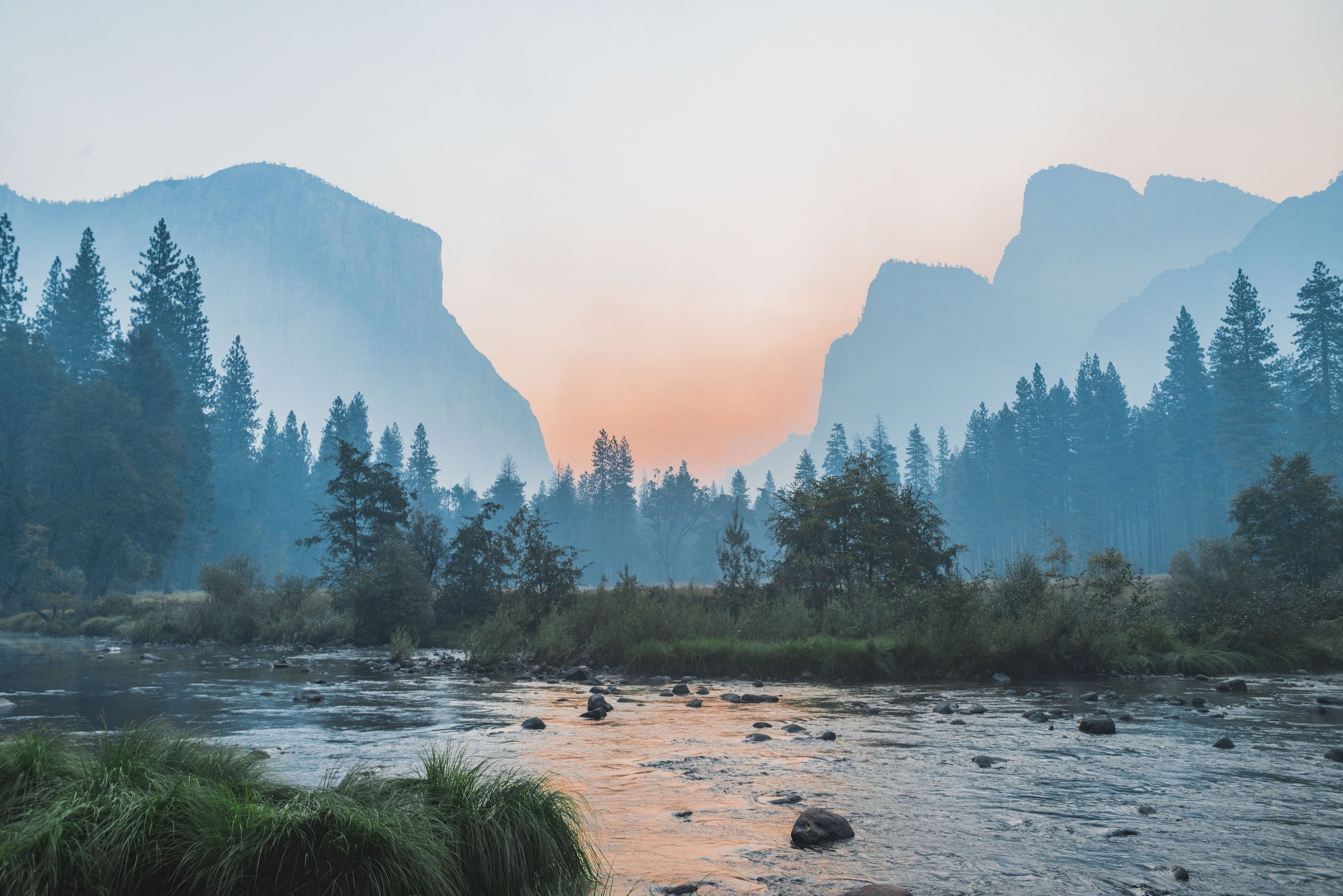 Mountain landscape with trees and and river in the foreground.