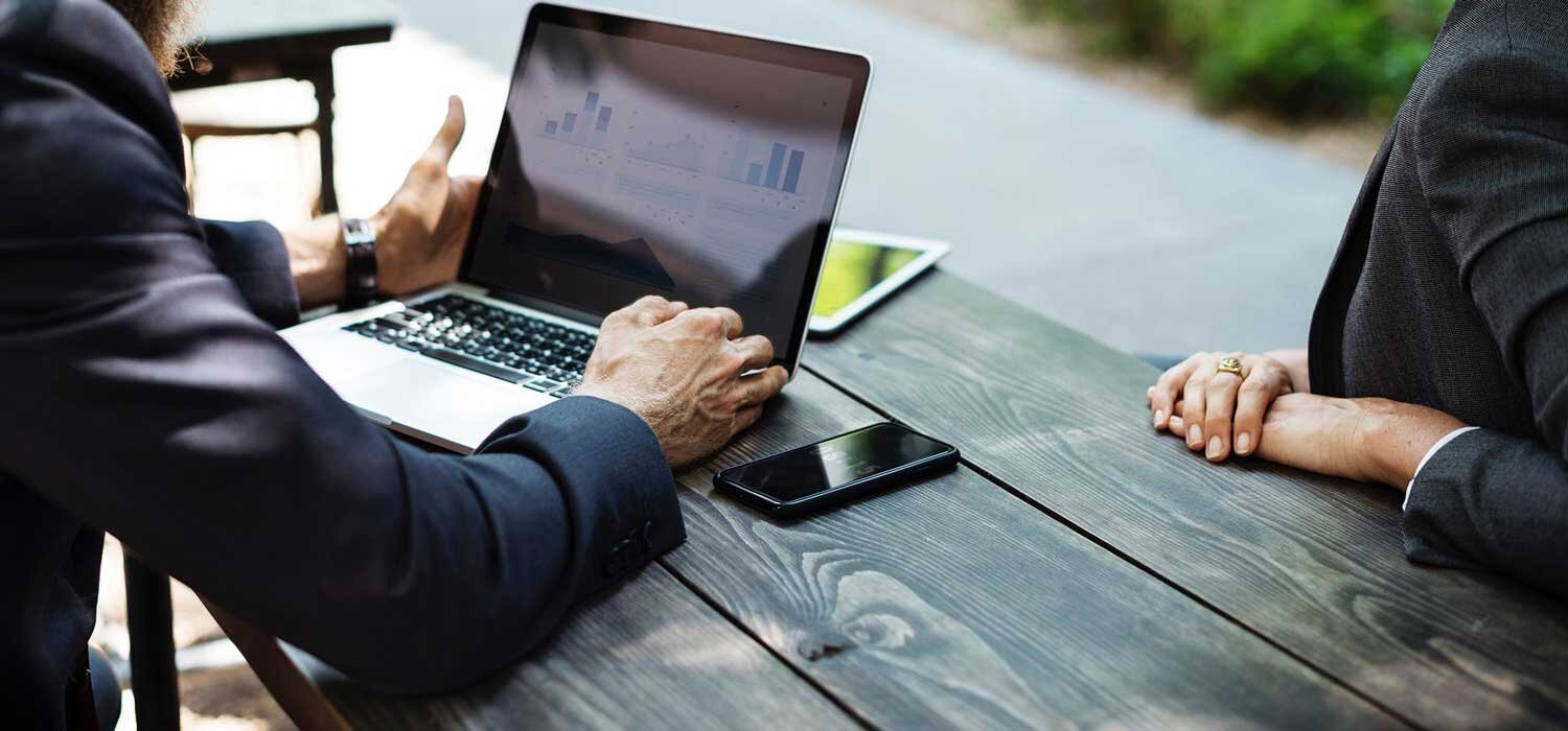 Two business people work outside at a table.