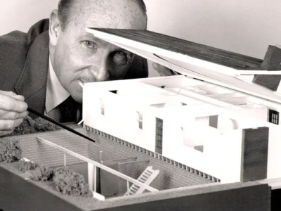 Ken Austin pointing to a model of a house.