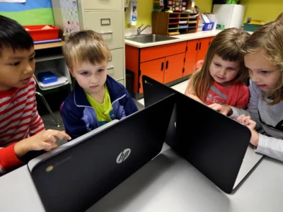 Children in school working together in front of computer screens.