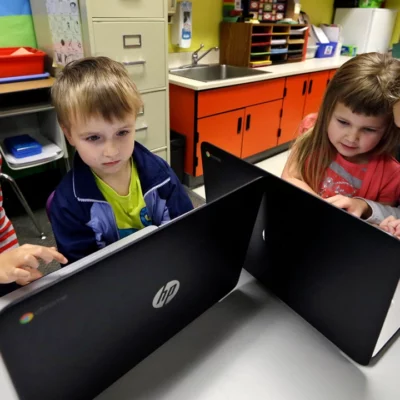 Children in school working together in front of computer screens.