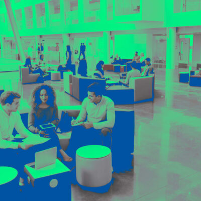 Numerous people working in small groups in a large atrium.